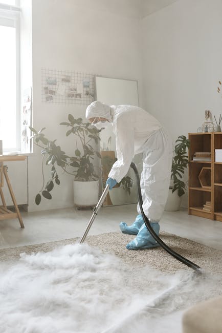 A person is kneeling on a patterned carpet in a residential setting, using a yellow and black vacuum cleaner for surface cleaning. Their hands are opening the vacuum's dust container to empty it, with